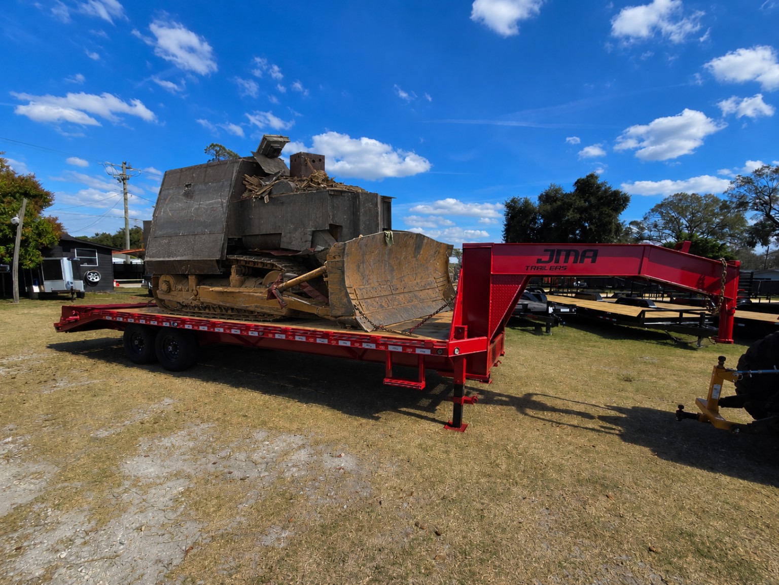 Red gooseneck trailer carrying a bulldozer